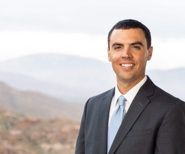 A Man Wearing A Suit And Tie Smiling At The Camera